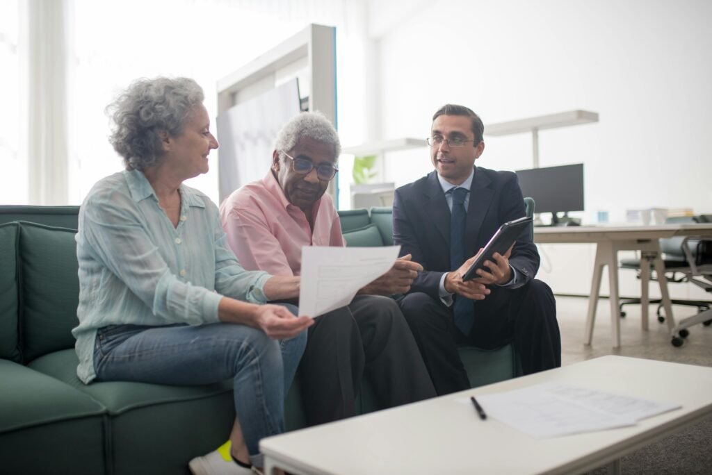 Senior couple discussing documents with a business advisor in a modern office setting.